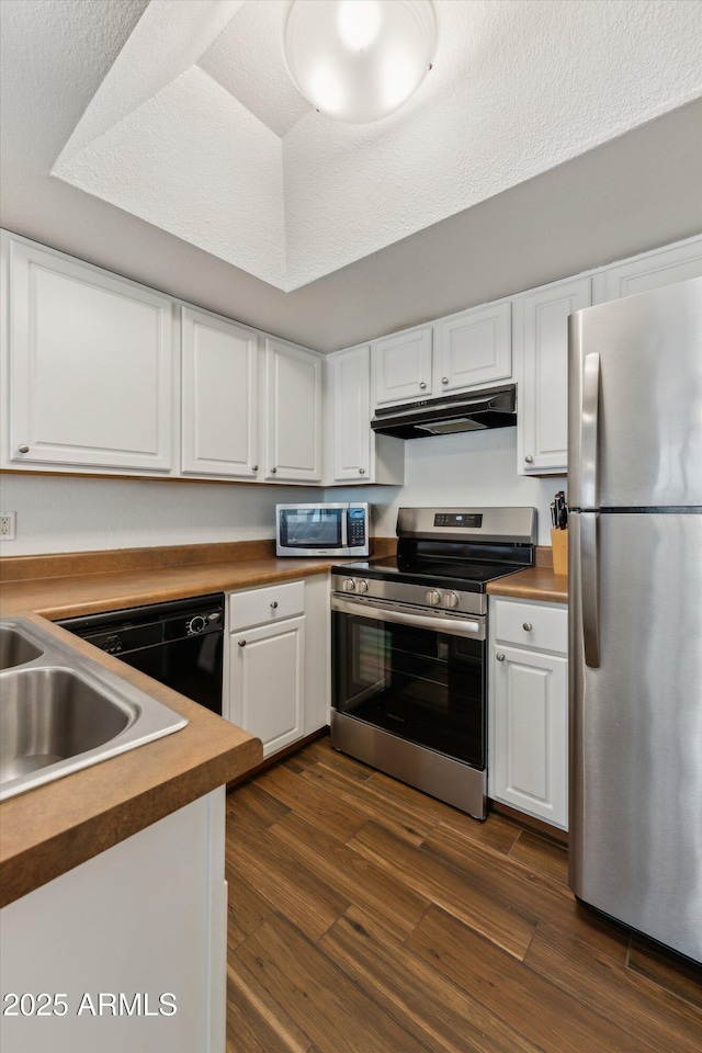 kitchen featuring white cabinets, under cabinet range hood, stainless steel appliances, and dark wood-style flooring