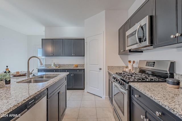 kitchen featuring light stone countertops, sink, light tile patterned flooring, and stainless steel appliances