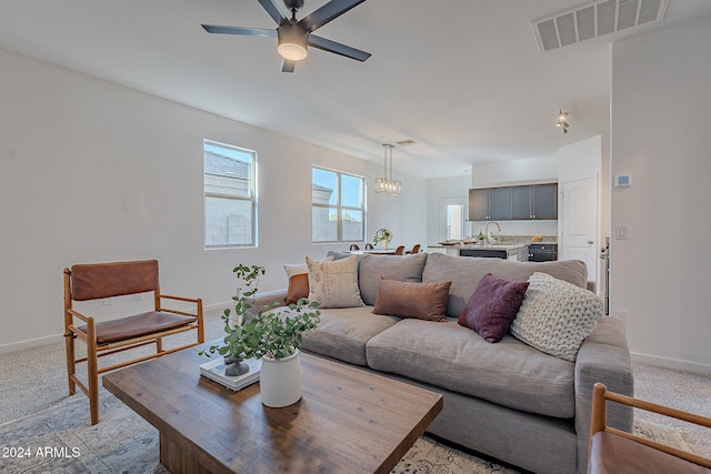 carpeted living room featuring ceiling fan and sink