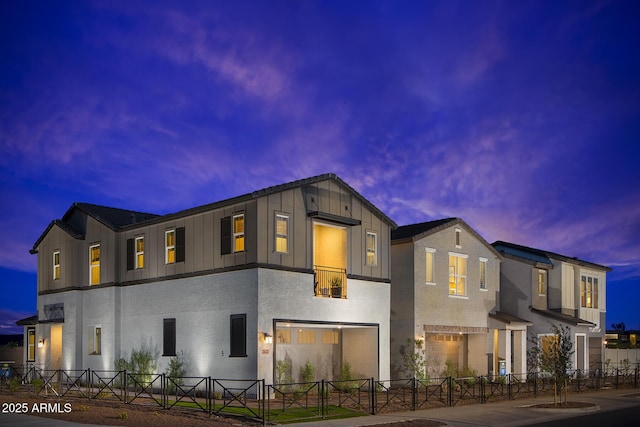 view of front of property featuring a garage, fence private yard, board and batten siding, and stucco siding