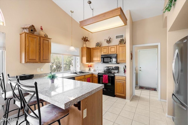 kitchen featuring black appliances, kitchen peninsula, sink, hanging light fixtures, and a breakfast bar area