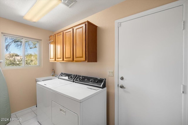 laundry room with cabinets, washer and clothes dryer, and light tile patterned flooring