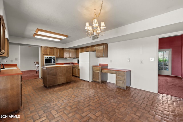 kitchen featuring hanging light fixtures, white refrigerator, stainless steel oven, sink, and a chandelier