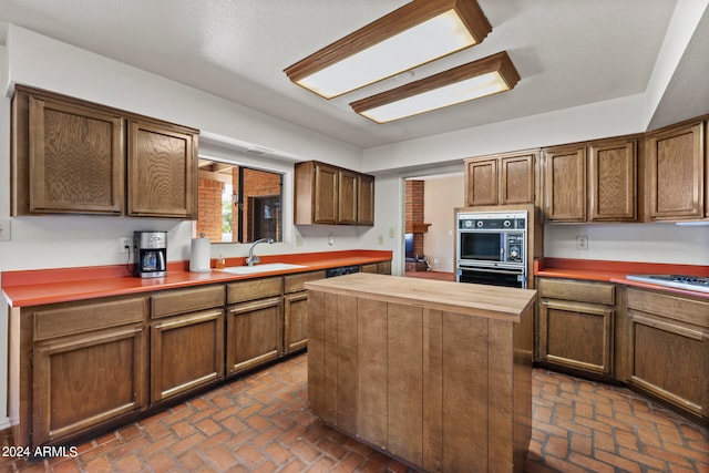 kitchen with stainless steel gas stovetop, sink, wood counters, and a kitchen island