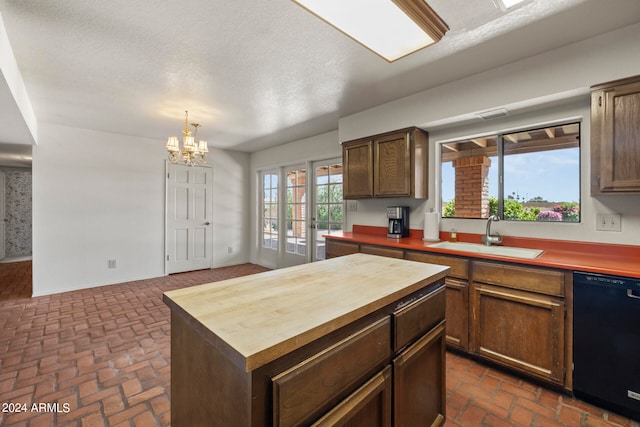 kitchen with black dishwasher, wooden counters, a textured ceiling, sink, and a chandelier