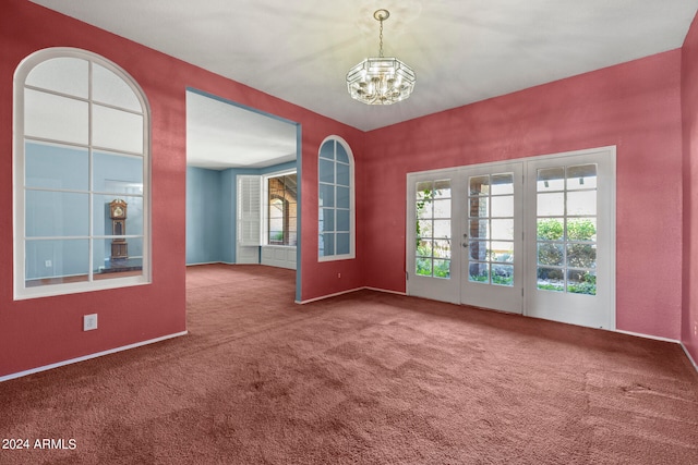 carpeted empty room featuring french doors and a notable chandelier