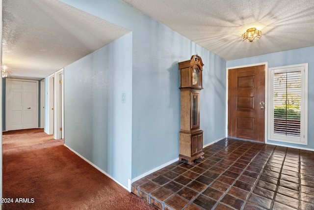 carpeted foyer entrance featuring a textured ceiling