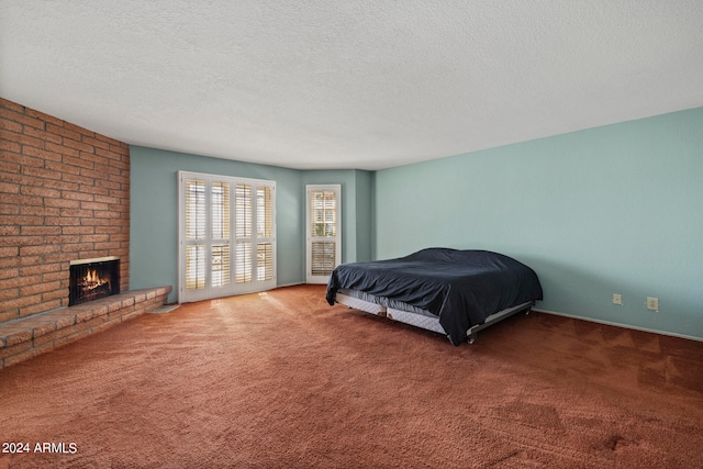 bedroom featuring a brick fireplace, carpet floors, and a textured ceiling