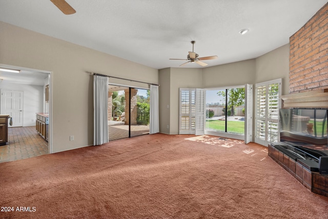 unfurnished living room with ceiling fan, carpet floors, and a fireplace