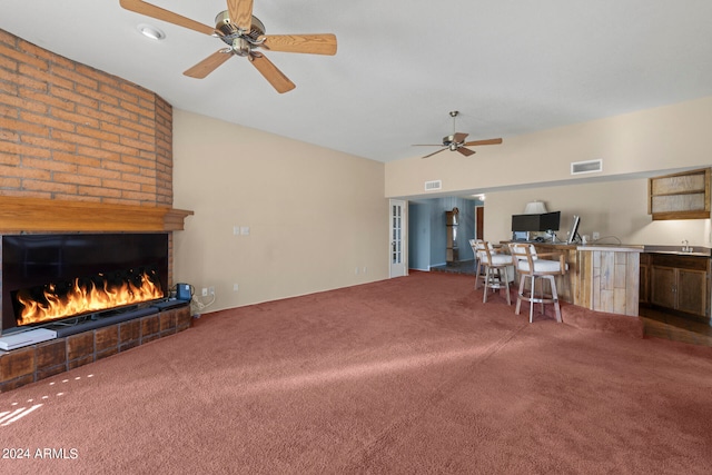 carpeted living room featuring ceiling fan, a fireplace, and sink