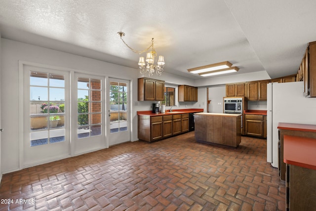 kitchen with pendant lighting, a notable chandelier, white fridge, a kitchen island, and oven