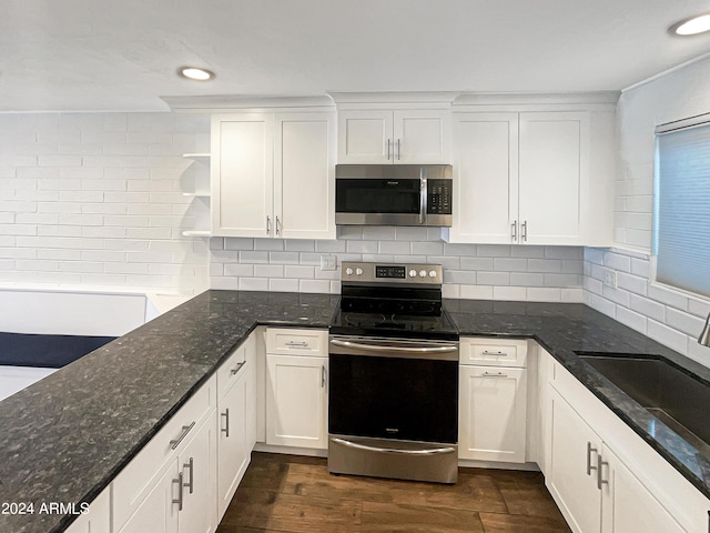 kitchen featuring stainless steel appliances, dark stone countertops, and white cabinets