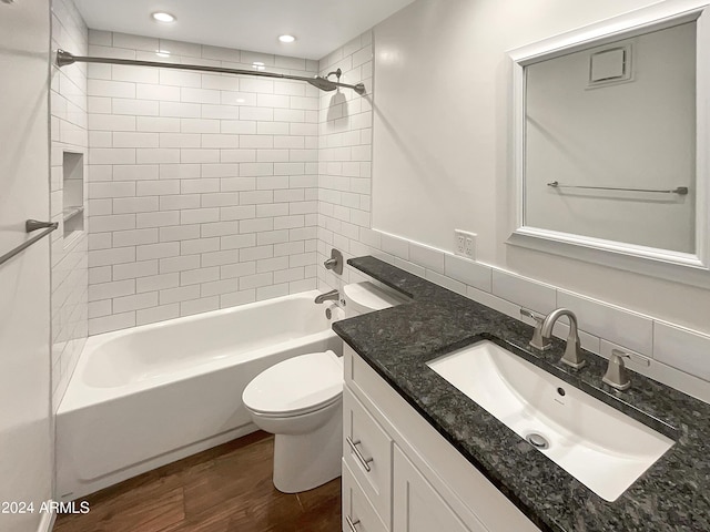 full bathroom with backsplash, hardwood / wood-style flooring, vanity, tiled shower / bath combo, and toilet