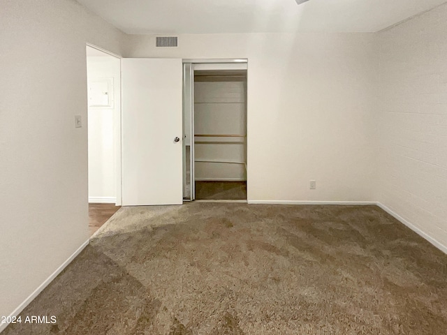 unfurnished bedroom with dark colored carpet and a closet