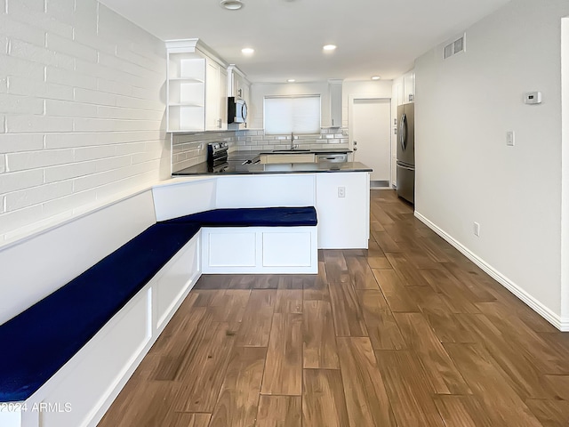 kitchen featuring sink, white cabinets, dark hardwood / wood-style flooring, kitchen peninsula, and stainless steel appliances