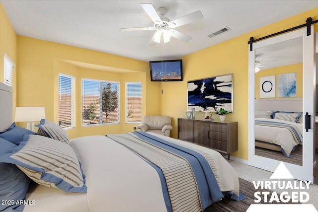 carpeted bedroom with multiple windows, a barn door, and ceiling fan