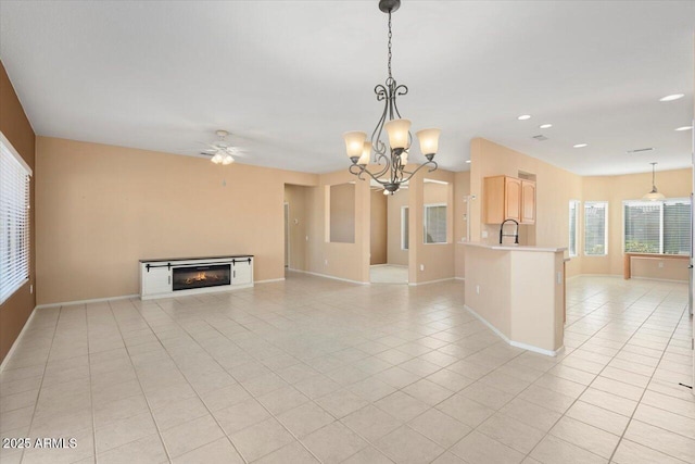 unfurnished living room with light tile patterned floors, ceiling fan with notable chandelier, and sink