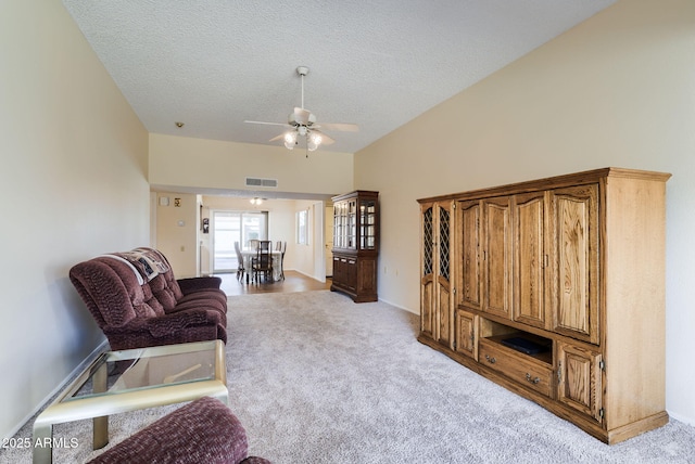 carpeted living room with ceiling fan, vaulted ceiling, and a textured ceiling