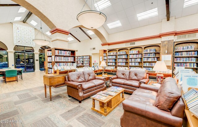 living room with high vaulted ceiling, beam ceiling, decorative columns, and hardwood / wood-style floors