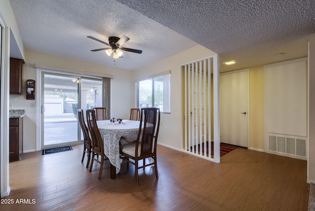 dining area with ceiling fan, wood-type flooring, and a textured ceiling