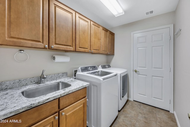 clothes washing area with separate washer and dryer, light tile patterned flooring, sink, and cabinets