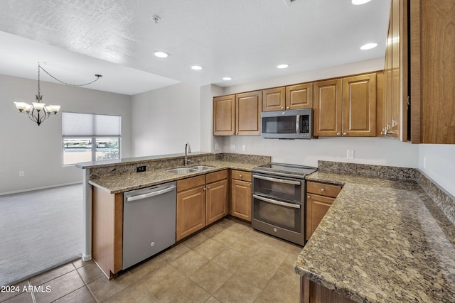 kitchen with sink, kitchen peninsula, decorative light fixtures, stainless steel appliances, and dark stone counters