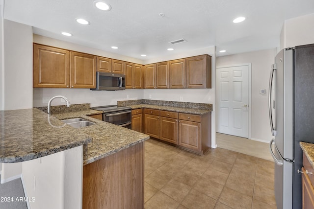 kitchen with dark stone countertops, a breakfast bar, kitchen peninsula, stainless steel appliances, and sink