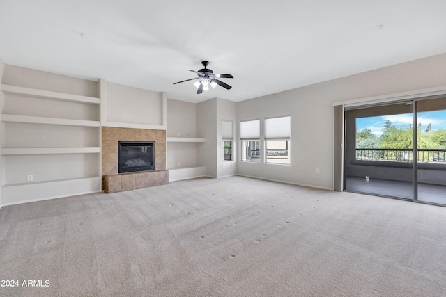 unfurnished living room featuring carpet flooring, a tiled fireplace, and a wealth of natural light