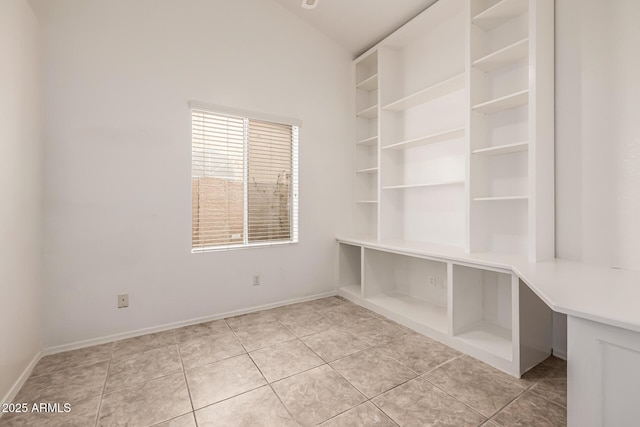 interior space featuring light tile patterned floors, baseboards, and lofted ceiling