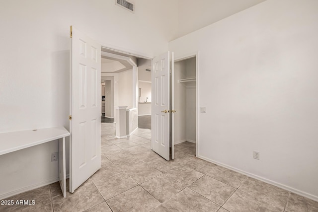 unfurnished bedroom featuring light tile patterned flooring, baseboards, visible vents, and a closet