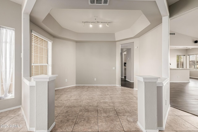 unfurnished room featuring a tray ceiling, light tile patterned flooring, baseboards, and visible vents