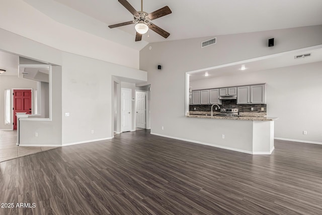 unfurnished living room featuring vaulted ceiling, visible vents, dark wood-style flooring, and ceiling fan