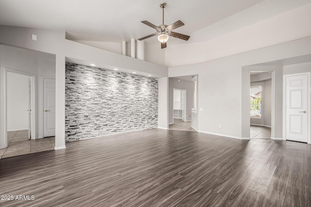 empty room with baseboards, wood finished floors, high vaulted ceiling, and ceiling fan