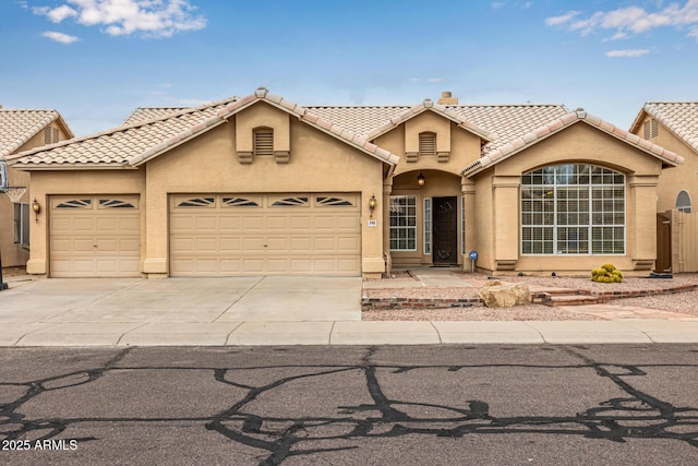 view of front facade with a tiled roof, a garage, driveway, and stucco siding