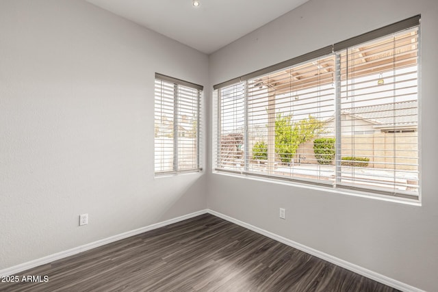 unfurnished room featuring baseboards and dark wood-style flooring