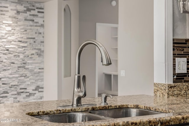 interior details with light stone counters and a sink