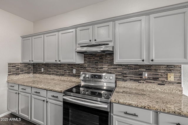 kitchen featuring light stone counters, electric range, dark wood-style flooring, decorative backsplash, and under cabinet range hood