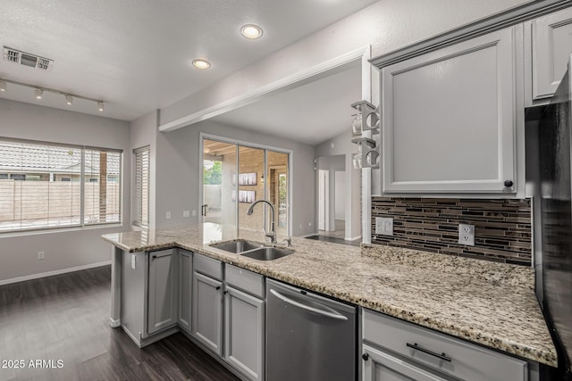 kitchen featuring a wealth of natural light, gray cabinetry, a sink, backsplash, and stainless steel dishwasher