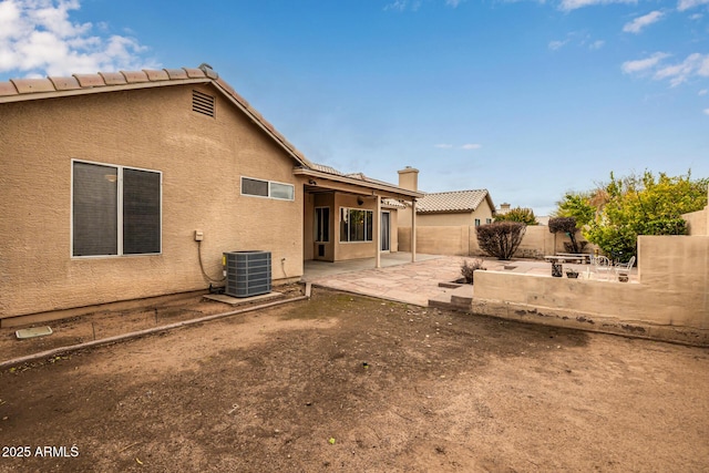 rear view of house featuring central air condition unit, stucco siding, a chimney, a fenced backyard, and a patio area