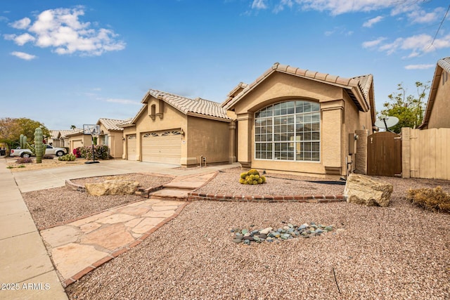 view of front of home featuring stucco siding, driveway, a gate, a garage, and a tiled roof