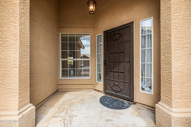 entrance to property featuring a patio area and stucco siding