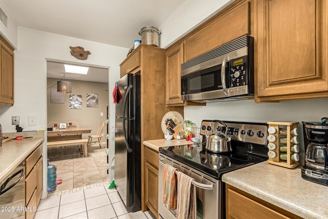 1951 E Del Sur Dr, Tempe, AZ 85283 - kitchen featuring appliances with stainless steel finishes, light tile patterned floors, light countertops, and brown cabinets