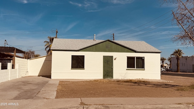 view of front of home with a shingled roof and fence