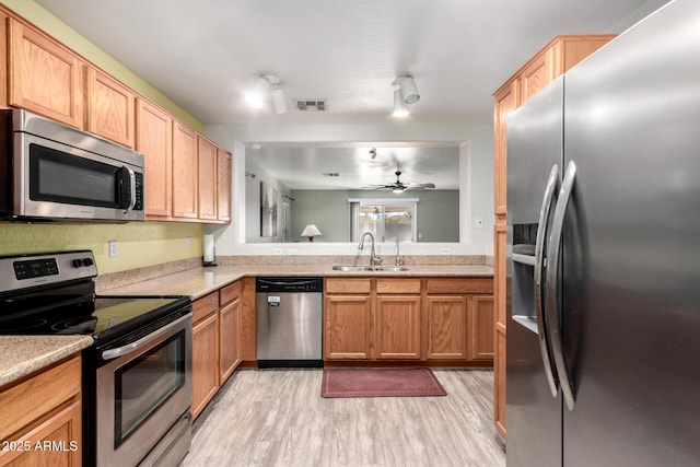 kitchen with sink, stainless steel appliances, and light wood-type flooring