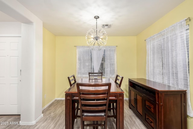 dining area with light wood-type flooring and an inviting chandelier