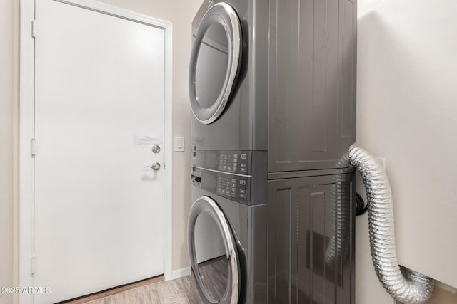 laundry room featuring stacked washer and dryer and light hardwood / wood-style flooring