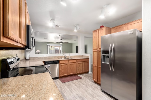 kitchen with sink, ceiling fan, appliances with stainless steel finishes, light stone counters, and light wood-type flooring