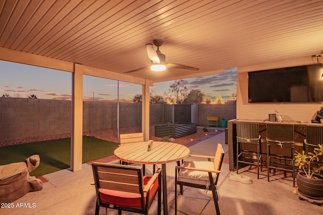 patio terrace at dusk with exterior bar and ceiling fan