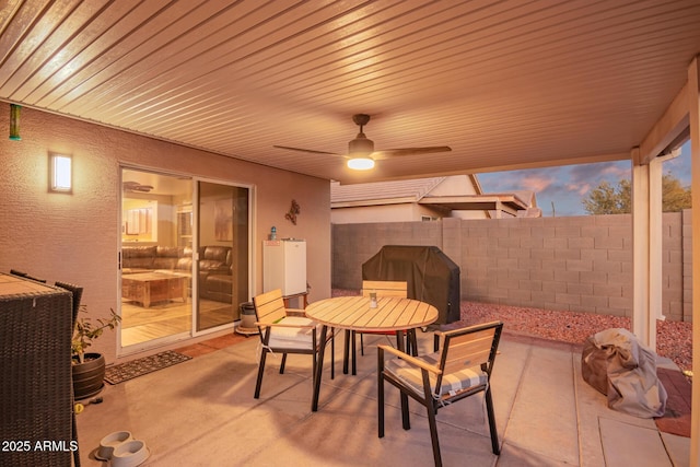 patio terrace at dusk with ceiling fan and a grill