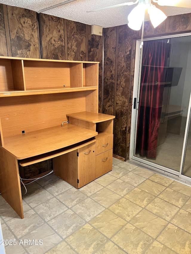 unfurnished office with stone finish floor, ceiling fan, and a textured ceiling